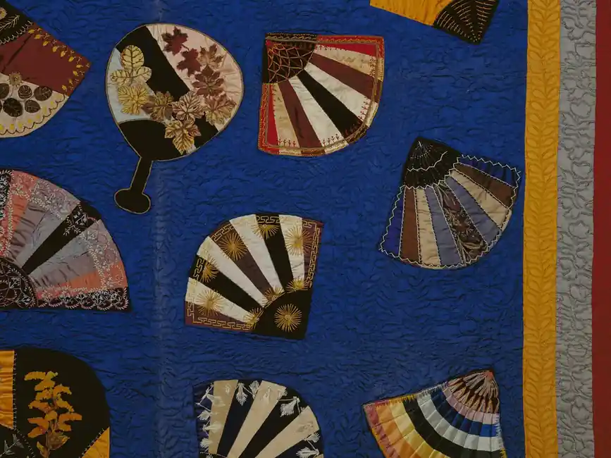 Hand-sewn appliqué panel with striped fan shapes laid on a deep blue cotton ground