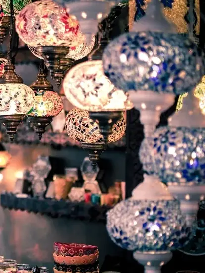 Mosaic glass lamp shades in cobalt, white and amber hanging in a cluster, lit from inside